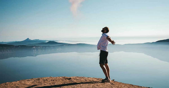 Man overlooking an ocean view with arms out celebrating freedom
